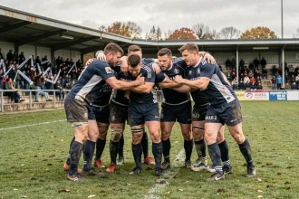 Joueurs de rugby en formation avant un match de Nationale 2, maillots bleu marine et blanc dans un stade régional français