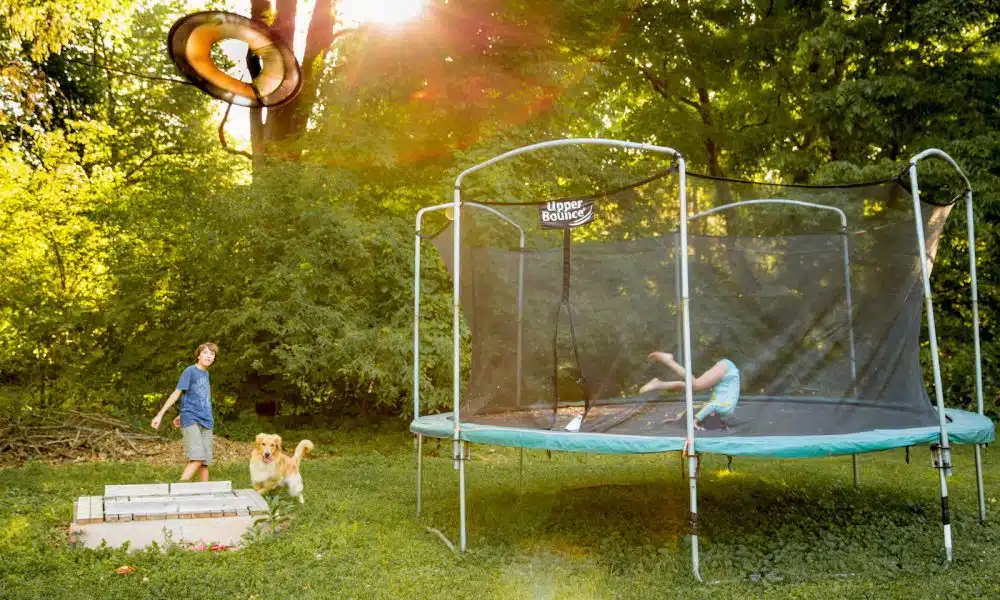 two children playing on a trampoline in a yard