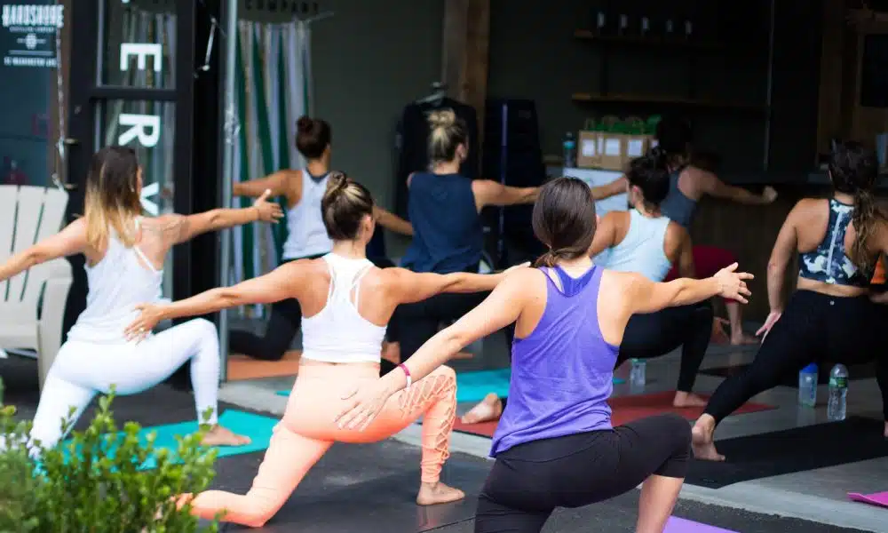 woman in white tank top and pink leggings doing yoga